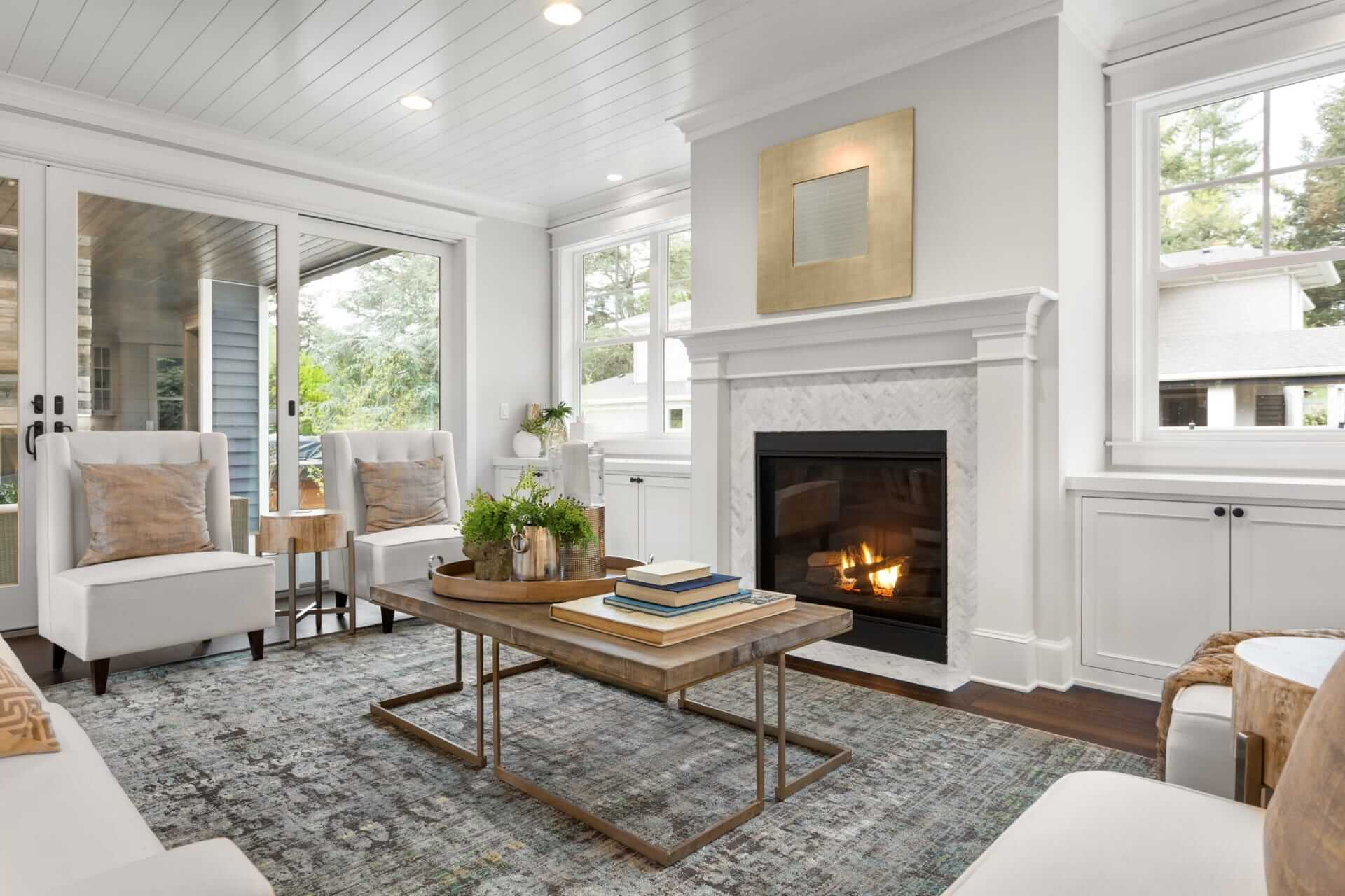 A bright living room with a lit fireplace and white built-ins